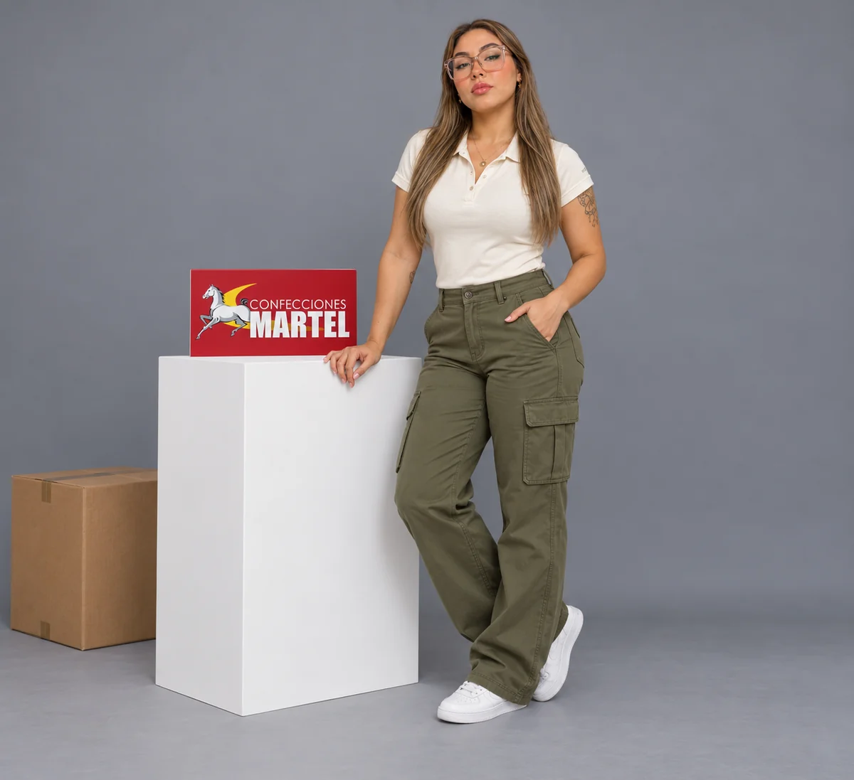 Mujer con gafas, polo blanco roto y pantalón oliva con bolsillos laterales de tapa en estudio.