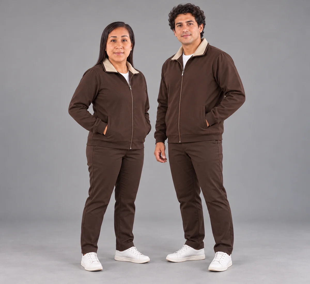 Mujer y hombre con casacas chocolate de cuello interior beige y pantalones a juego.