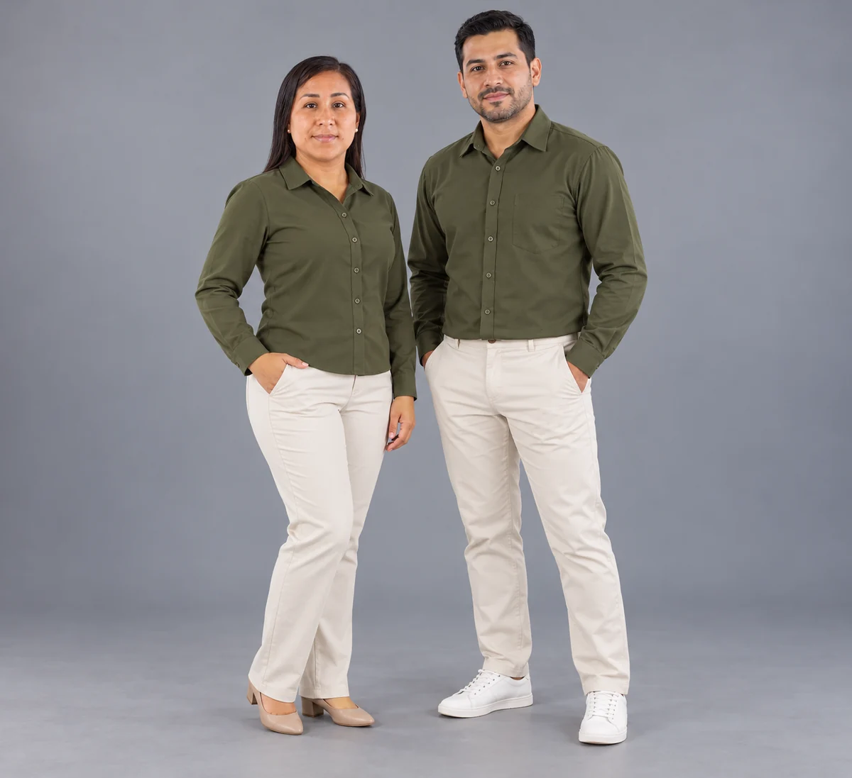Mujer y hombre con blusa y camisa verde oliva y pantalones claros en estudio.